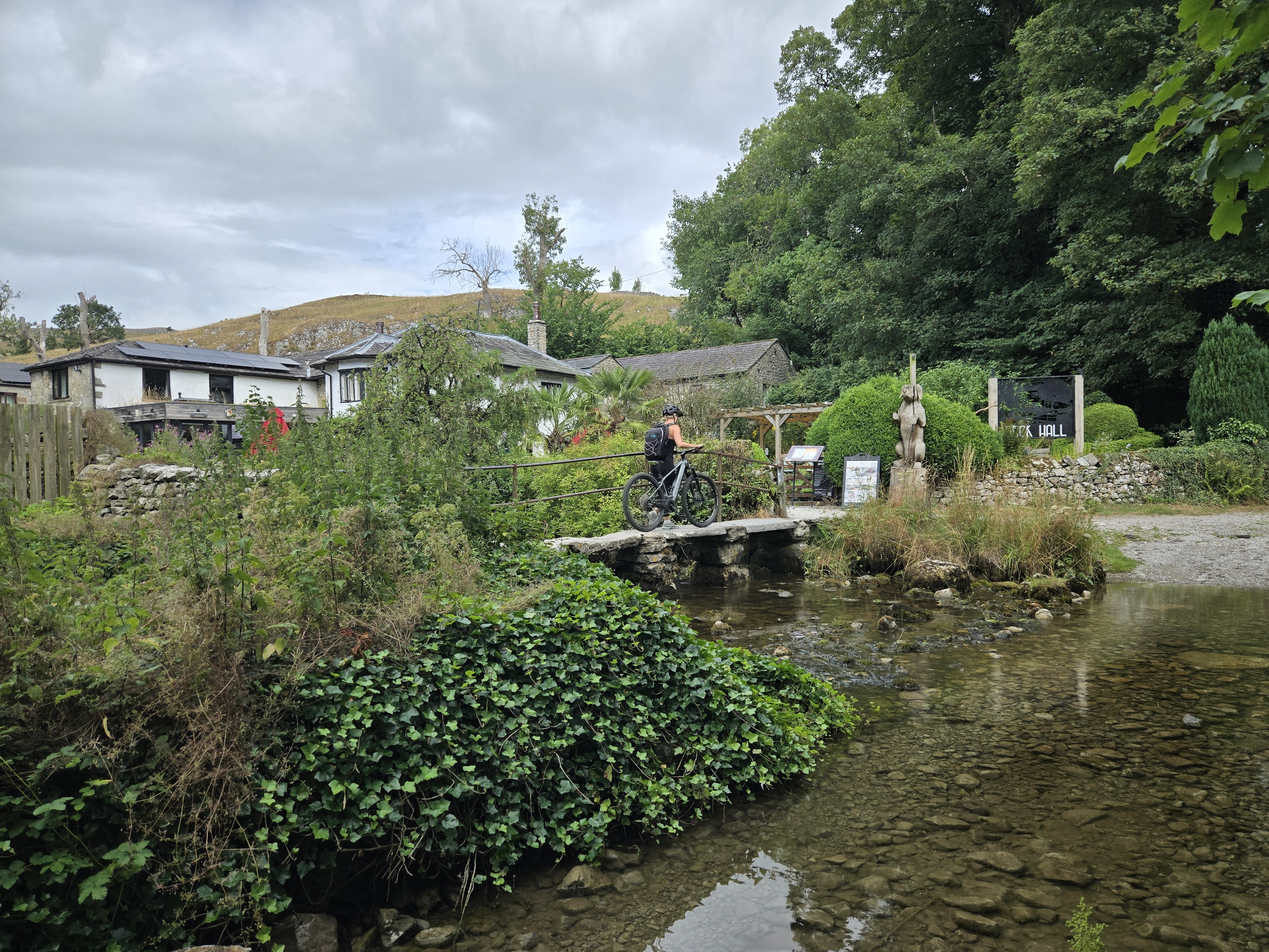 Cyclist crossing clapper bridge in Malham village