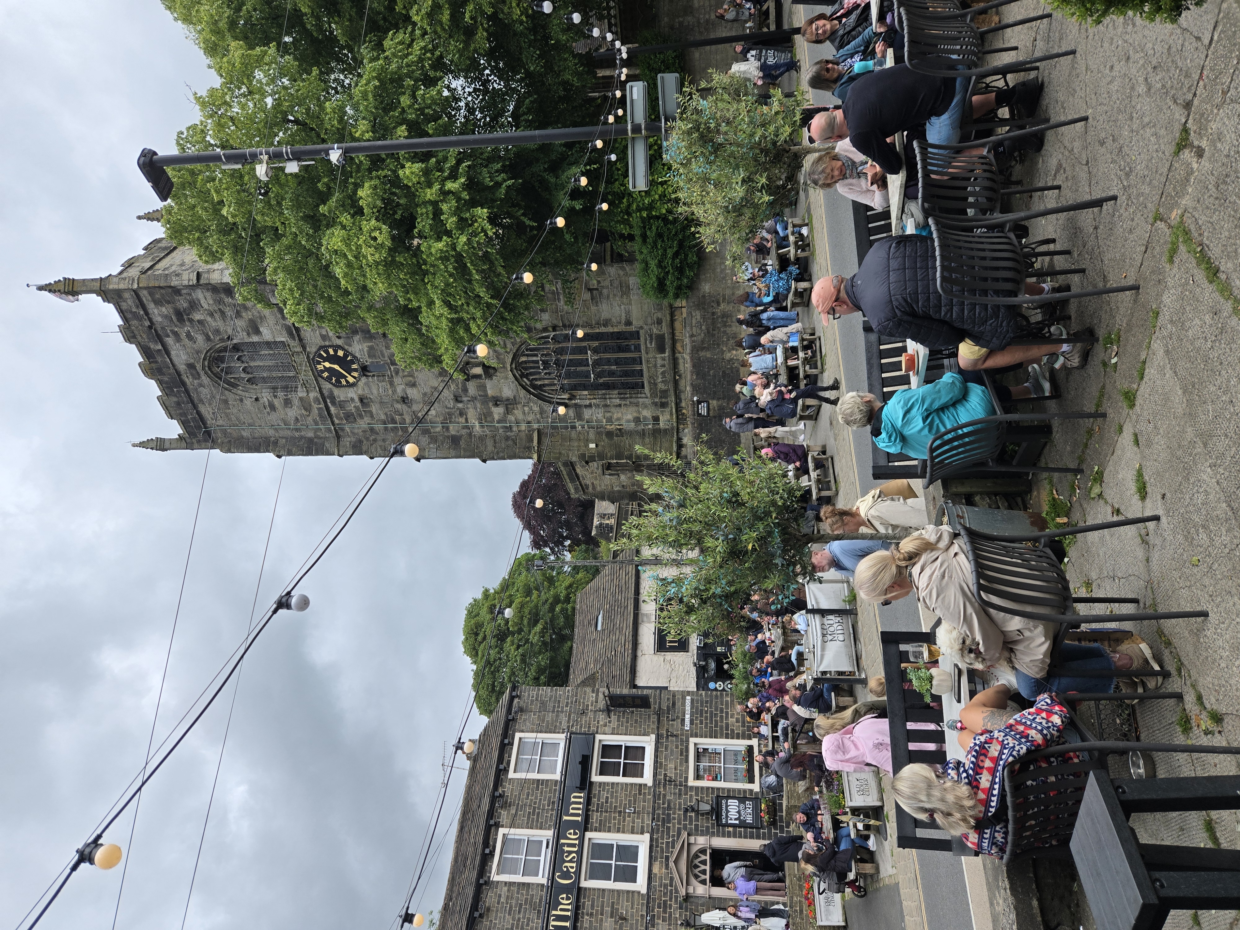 Pavement cafe with pub and church across road behind